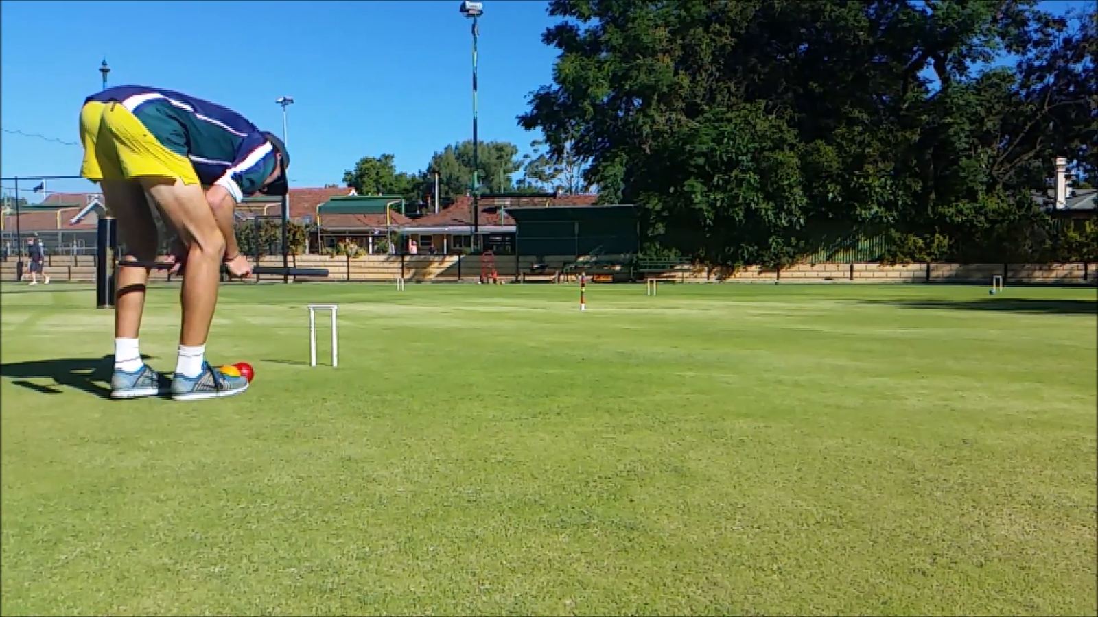A player bent over a mallet lining up a shot on a sunny lawn